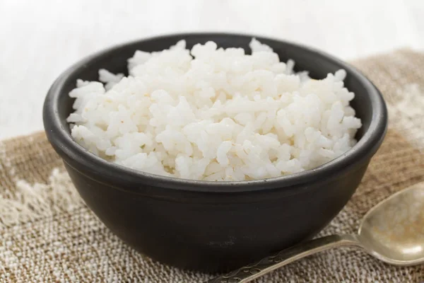 Arroz hervido en tazón negro en fondo de madera —  Fotos de Stock