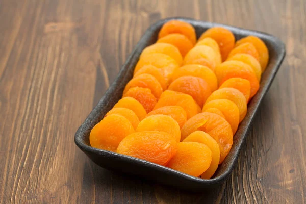 Dry apricot on black plastic dish — Stock Photo, Image