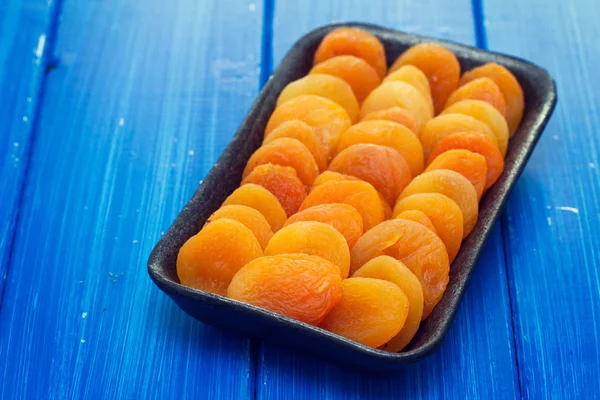 Torr aprikos på svart plast maträtt — Stockfoto