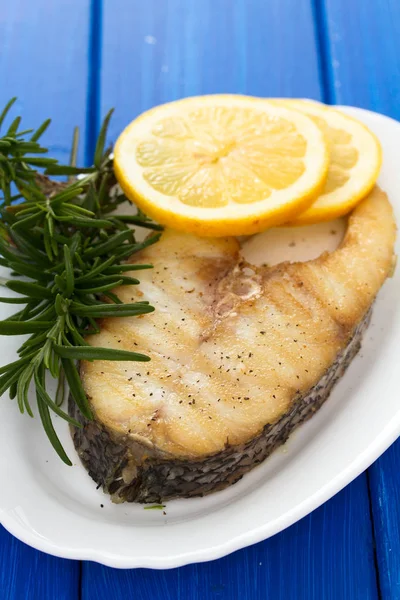 Gegrillter Fisch mit Zitrone in weißer Schale auf hölzernem Hintergrund — Stockfoto