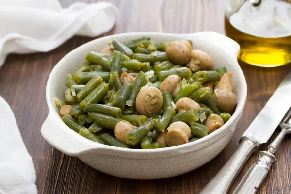 Green beans with mushrooms in dish on wooden background — Stock Photo, Image