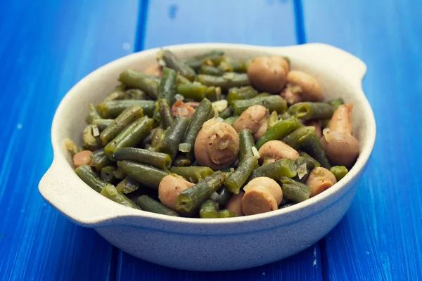 Green beans with mushrooms in dish on wooden background — Stock Photo, Image