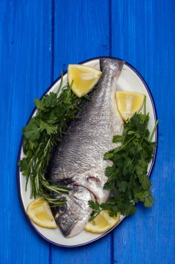 otlar ve çanak üzerinde ahşap arka plan üzerinde limon ile çiğ balık