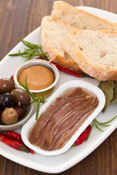 Sardellen, Oliven, Brot und Fischpastete auf Teller — Stockfoto