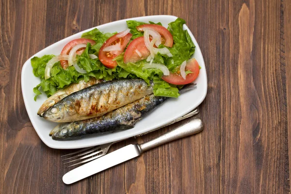 Gegrillte Sardinen mit Salat auf weißem Teller — Stockfoto