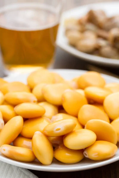 Altramuces salados en plato blanco y caracoles con vaso de cerveza — Foto de Stock