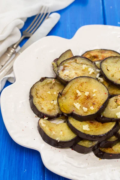 Melanzane fritte con aglio su piatto bianco su sfondo di legno — Foto Stock