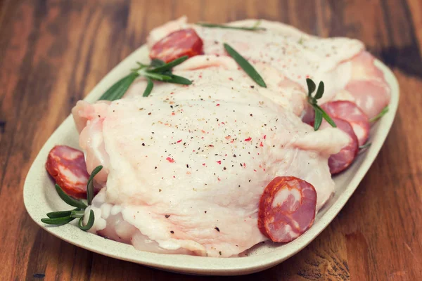 Raw chicken with smoked sausage and rosemary on white dish — Stock Photo, Image