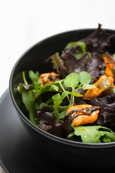 Salade aux moules dans un bol noir — Photo