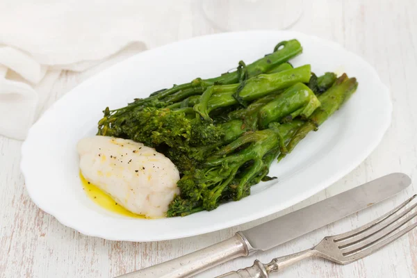 Boiled fish with greens and olive oil on white dish — Stock Photo, Image