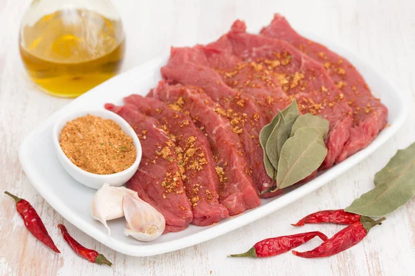 Raw meat with herbs on white dish on wooden background — Stock Photo, Image