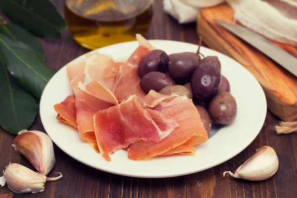 Jamon with olives on white plate — Stock Photo, Image