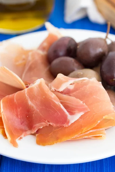 Jamon with olives on white plate — Stock Photo, Image