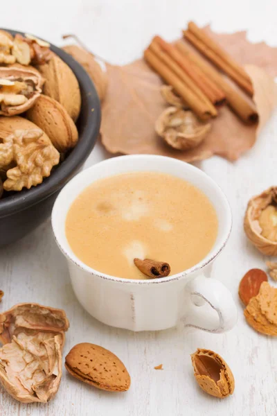 A cup of coffee and nuts on wooden background — Stock Photo, Image