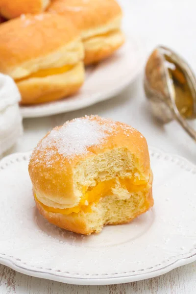 Ciambelle con crema di uova in scatola di carta bianca su sfondo di legno — Foto Stock