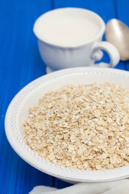 Beyaz kase ve süt, bir fincan yulaf ezmesi