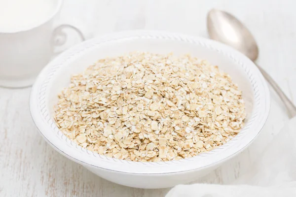 Beyaz kase ve süt, bir fincan yulaf ezmesi 