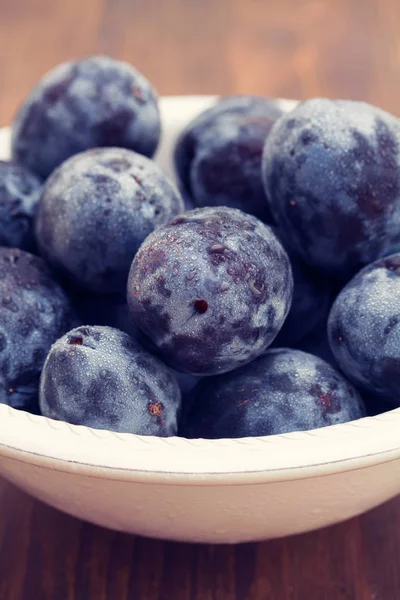 kahverengi zemin üzerine beyaz kase taze erik