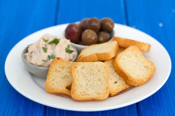 Toasts mit Fischpastete und Oliven auf weißem Teller — Stockfoto