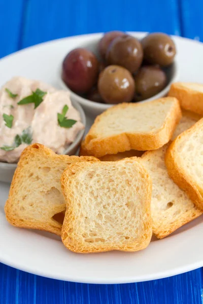 Tostadas con paté de pescado y aceitunas en plato blanco — Foto de Stock