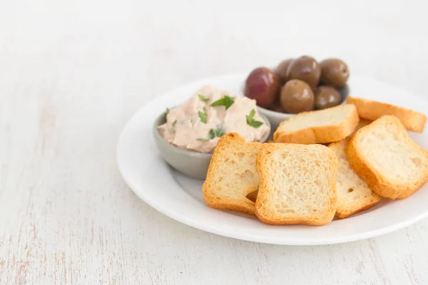 Toasts mit Fischpastete und Oliven auf weißem Teller — Stockfoto