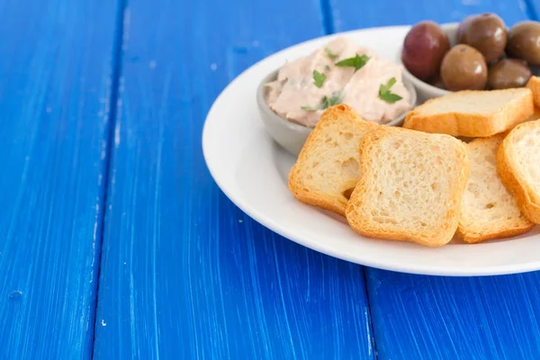 Тосты с рыбным паштетом и оливками на белой тарелке — стоковое фото