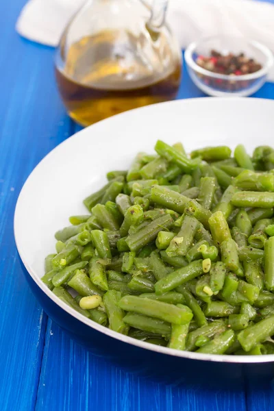 Green beans on frying pan on wooden background — Stock Photo, Image