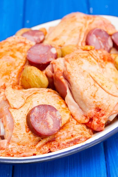 Raw marinated chicken with smoked sausages on dish — Stock Photo, Image