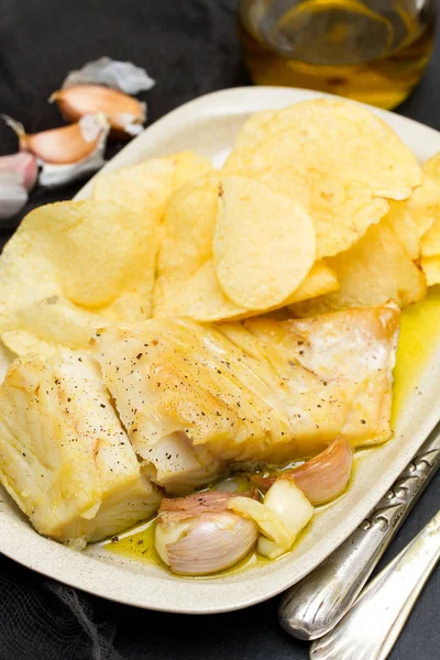 Ikan kod goreng dengan bawang putih dan kentang di atas piring — Stok Foto