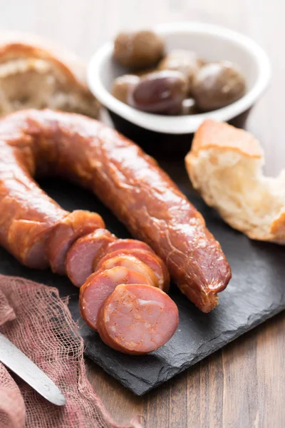 Smoked sausages with bread on black ceramic board — Stock Photo, Image