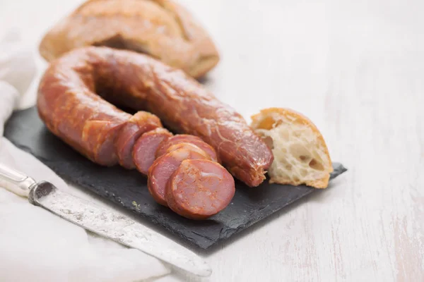 Saucisses fumées avec pain sur carton céramique noire — Photo