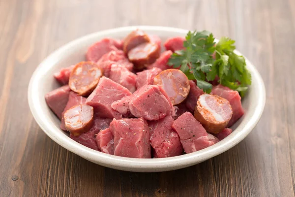 Carne cruda con salchichas ahumadas en plato — Foto de Stock