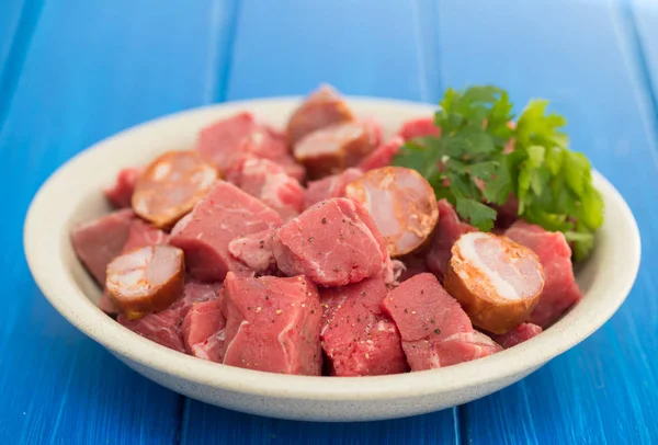 Carne cruda con salsicce affumicate su piatto — Foto Stock