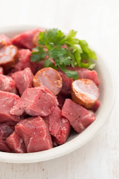 Carne cruda con salsicce affumicate su piatto — Foto Stock