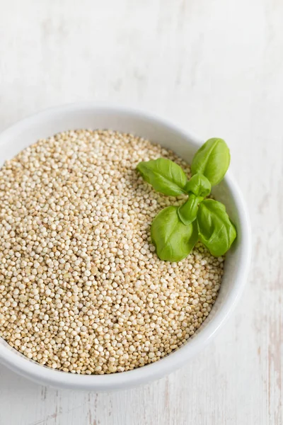 Syrového quinoa v bílé míse na bílém pozadí dřevěná — Stock fotografie