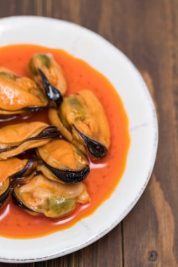 ahşap arka plan üzerinde beyaz çanak üzerinde soslu midye