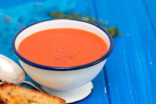 Sup tomat dalam hidangan putih dengan roti di latar belakang biru — Stok Foto
