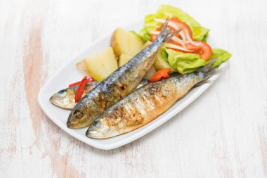 haşlanmış patates ve salata beyaz plaka üzerinde ızgara sardalya