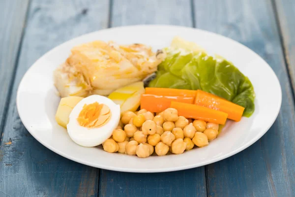 Варена тріска риба з картоплею, морквою, капустою, нутом і яйцем — стокове фото