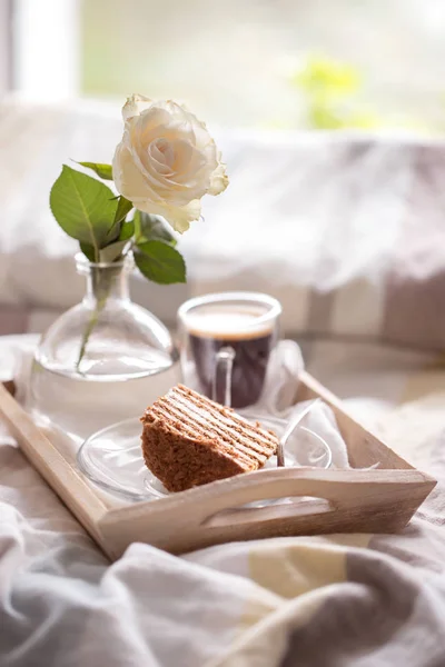 cake with coffee and flower in tray on bed