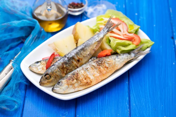 Grilled sardines with boiled potato and salad on white plate — Stock Photo, Image