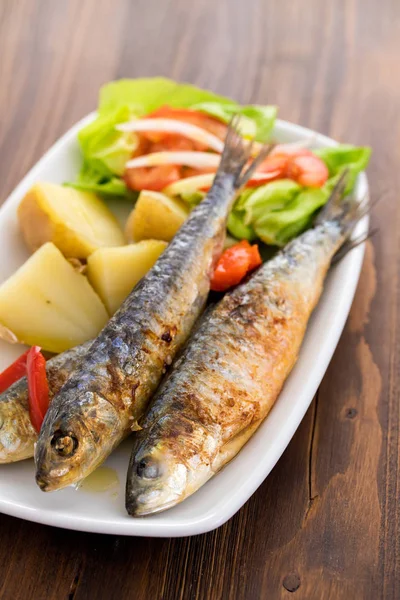 Gegrillte Sardinen mit Salzkartoffeln und Salat auf weißem Teller — Stockfoto