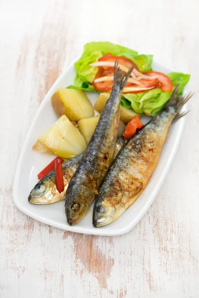 Sardines grillées à la pomme de terre bouillie et salade sur assiette blanche — Photo