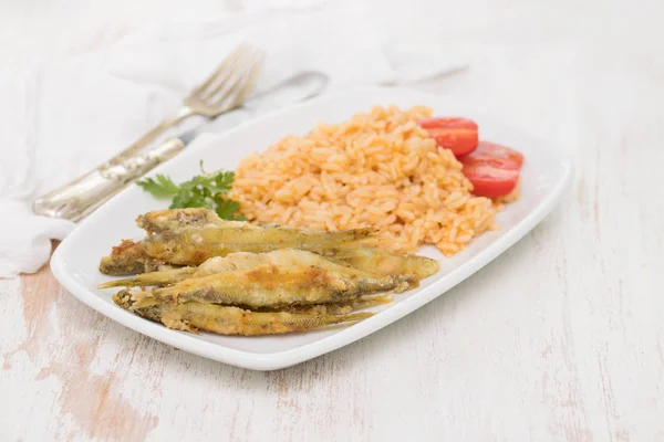 Éperlans frits avec riz tomate sur plat blanc — Photo