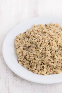 ahşap arka plan üzerinde beyaz tabakta haşlanmış quinoa