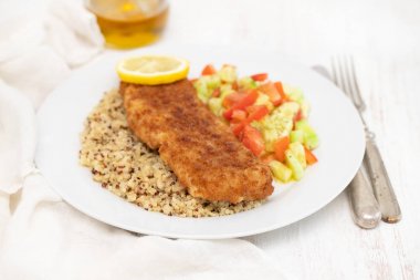 Kızarmış Balık salatası, qiuinoa ve beyaz plaka üzerinde limon ile