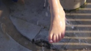 Çocuk dışarıda suyla oynuyor.