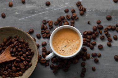 Tahıllı bir fincan kahve ve seramik taşlı tahta kaşık.