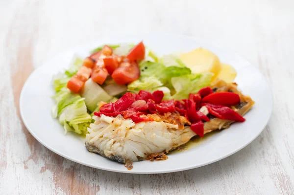 Рыба треска с красным перцем, картофель и салат на белой тарелке на cer — стоковое фото