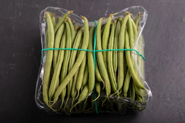 Green beans in plastic box on ceramic background — Stock Photo, Image